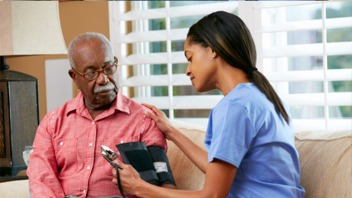 caregiver checking blood pressure of old man